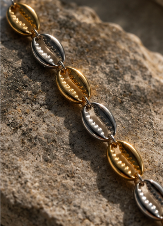 Close-up of gold and silver cowrie shell links on the mixed metal Island Cowrie Bracelet.