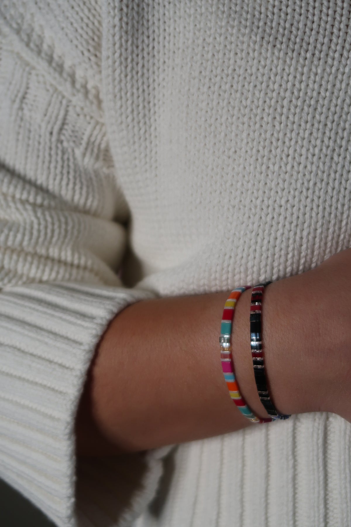 Bat Brothers and Fantasy Bookshelf Bracelet Second Edition with colorful glass beads and silver-toned accents, worn together with a cream knit sweater.