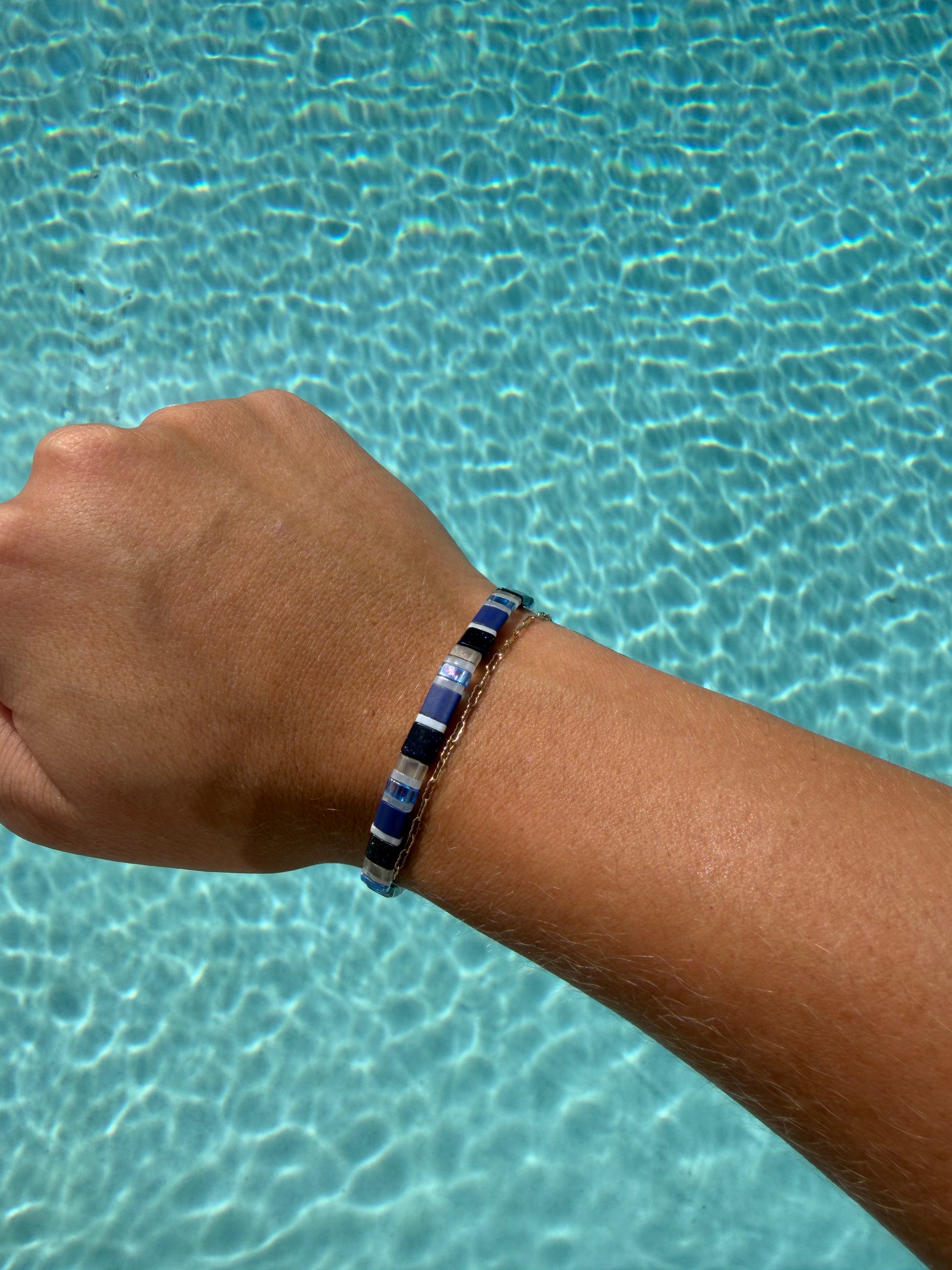 Spotted Eagle Ray-inspired glass-bead bracelet worn on a wrist over blue pool water.