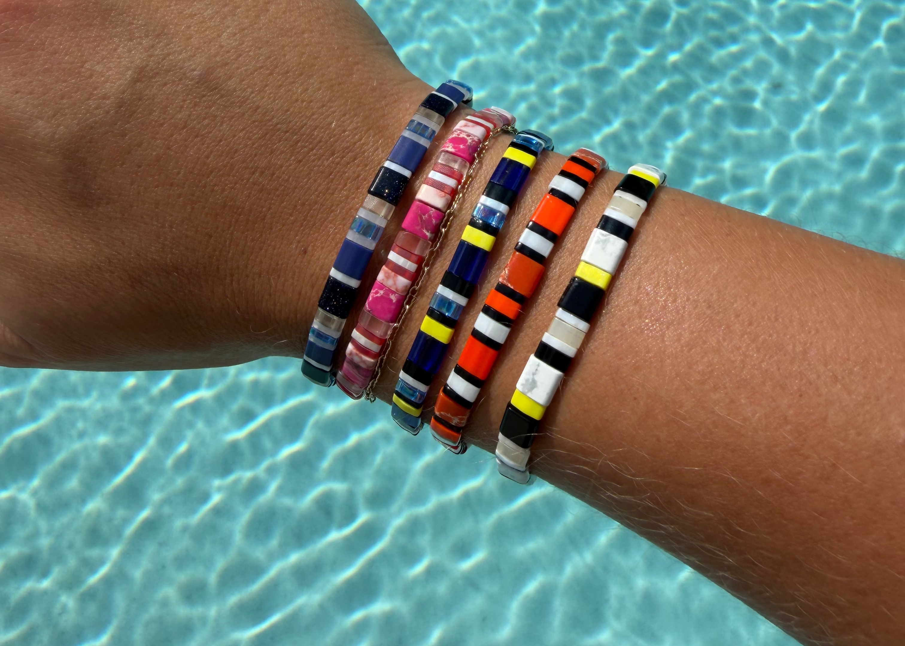 Five handmade glass-bead bracelets from The Reef Edit, inspired by a pink sea star, clownfish, spotted eagle ray, Moorish idol, and regal blue tang.