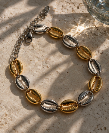 Mixed metal Island Cowrie Bracelet with alternating gold and silver cowrie shell links.